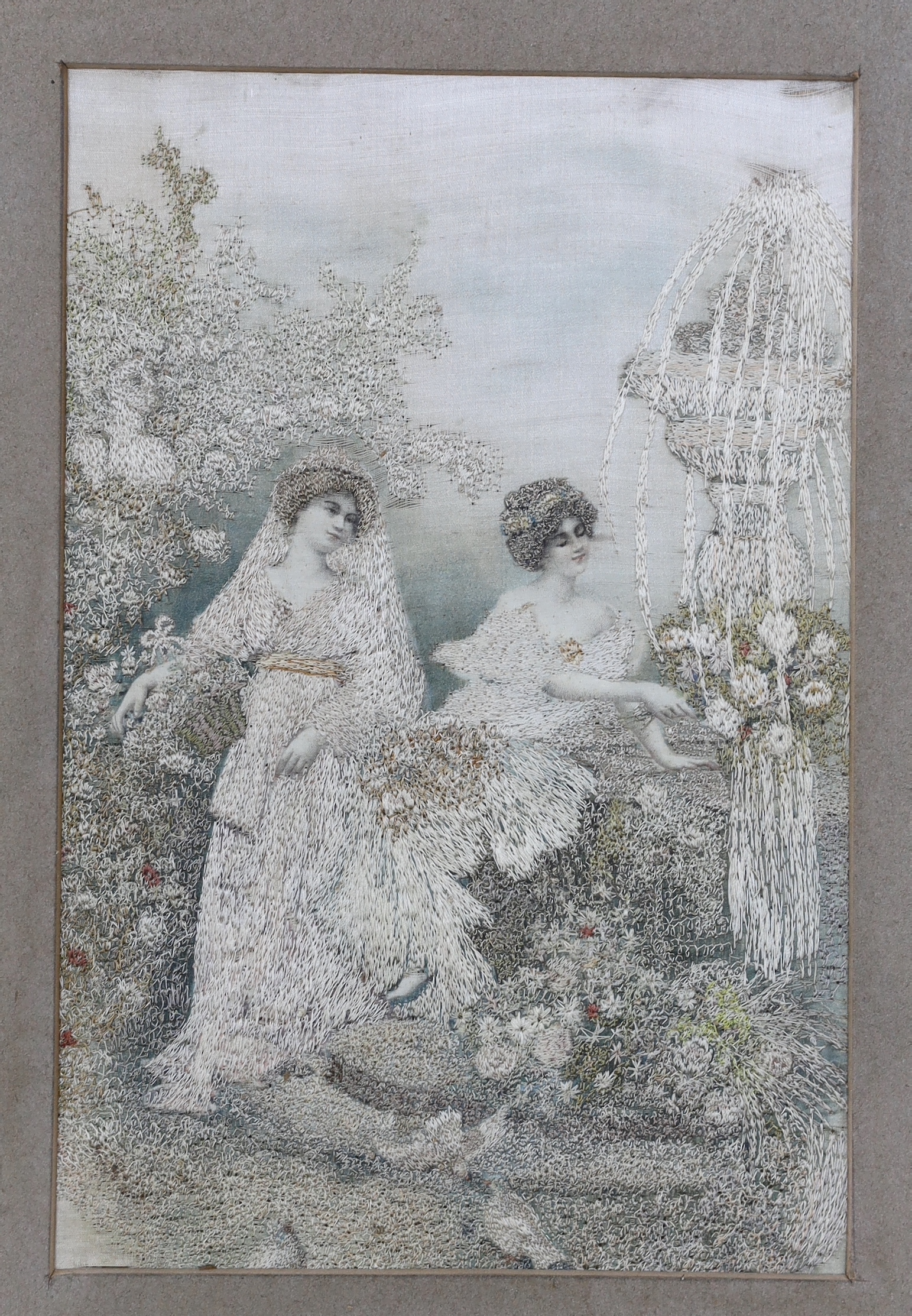 A pair of framed silk needlework panels, one of two ladies feeding a swan, the other of them cutting flowers in a garden, 13.5cm wide x 22.5cm high